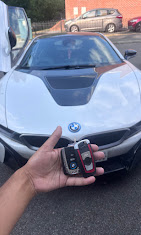Auto Mobile Key Masters technician holding a newly coded BMW display key in front of a white BMW i8